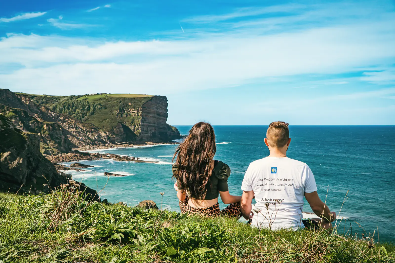 Rigina und Andreas blicken von einer Klippe auf das Meer